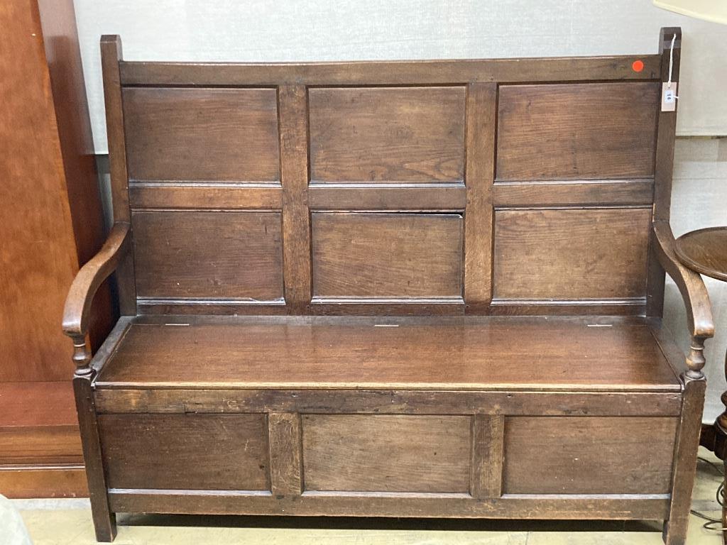 A mid 18th century panelled oak hinged box seat settle, length 148cm, depth 56cm, height 122cm